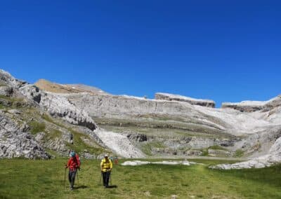 Excursionistas atravesando un sendero en el Valle de Ordesa entre vegetación y paredes escarpadas