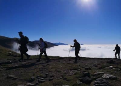 Excursionistas caminando sobre monte con niebla cubriendo el valle en Ordesa